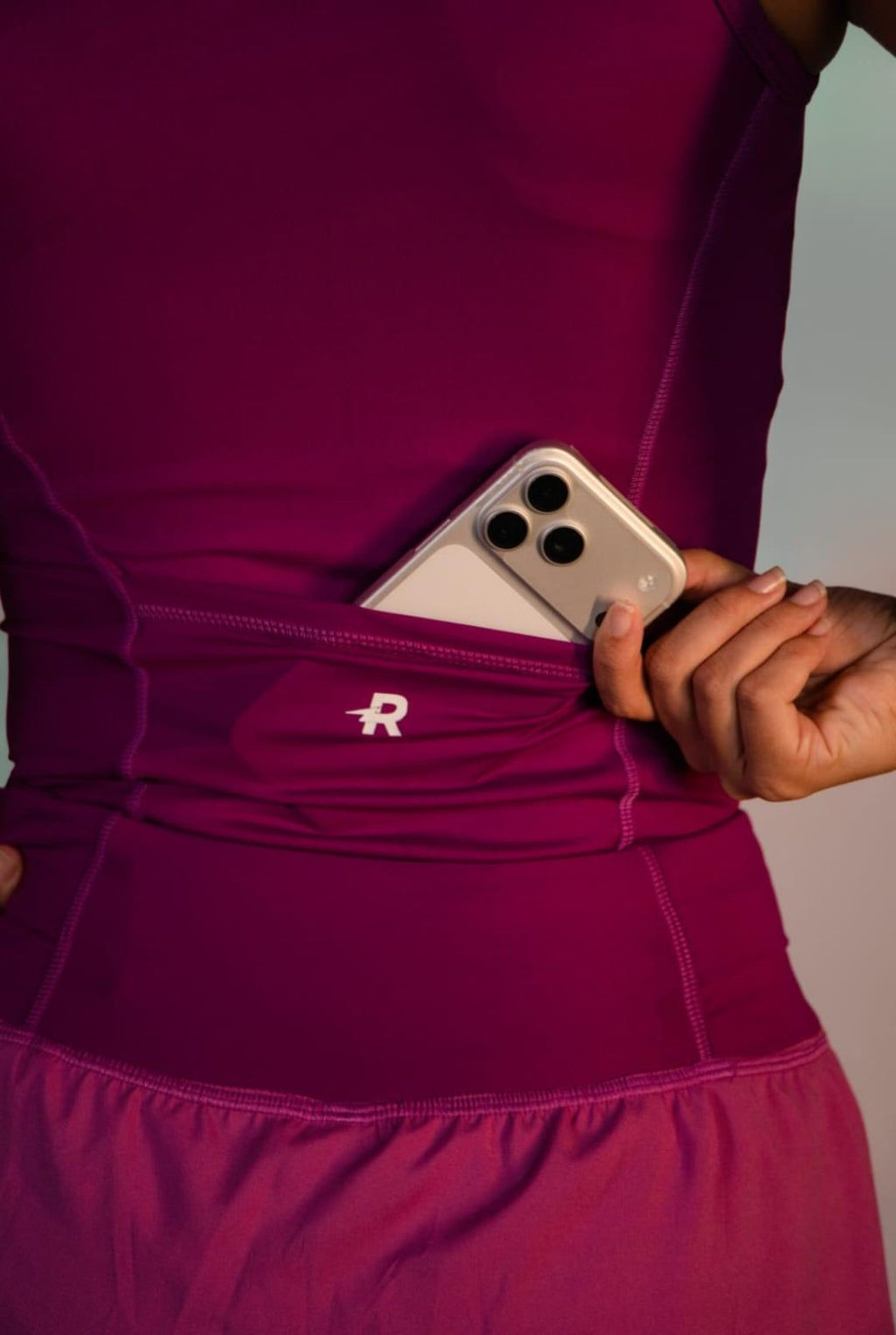 Regata de Compressão feminina Runaholic, cor roxa, detalhe do celular no bolso